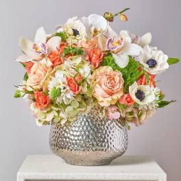 Mixed bouquet of peach and white flowers in a silver vase