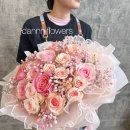 Large bouquet of pink and peach roses wrapped in pale pink paper