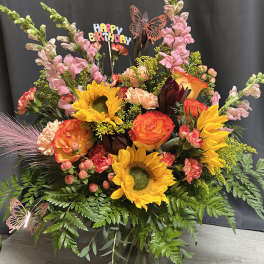 Colorful bouquet with sunflowers, roses, and pink snapdragons in a glass vase