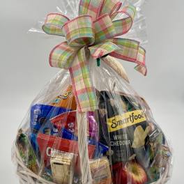 Gift basket of assorted snacks wrapped in clear cellophane with a plaid bow