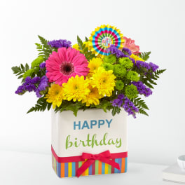 Birthday flower arrangement in a striped gift box with a ribbon