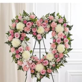 Heart-shaped floral wreath with pink and white flowers on a stand