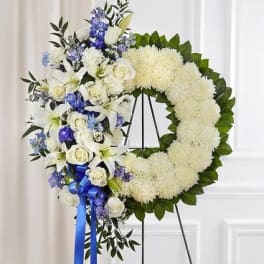 White and blue funeral wreath with roses and lilies on an easel