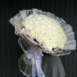 Large bouquet of white roses wrapped in clear plastic with ribbon
