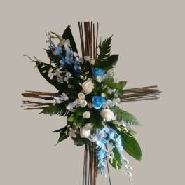 Cross-shaped floral arrangement with blue and white flowers on a wooden stand