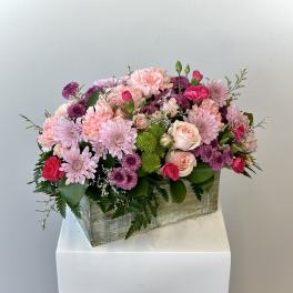 Pink and purple mixed flower arrangement in a wooden box