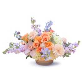 Pastel floral arrangement in a low wooden bowl