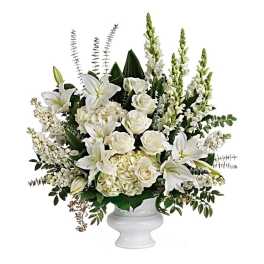 White lilies and roses arranged in a white pedestal vase