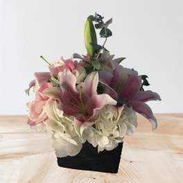 Pink lilies and white hydrangeas in a black container