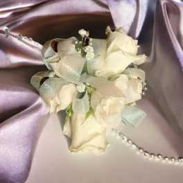 Small white rose corsage with silver ribbon on satin fabric