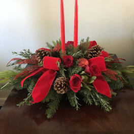 Red roses and candles arranged with pinecones and ribbon