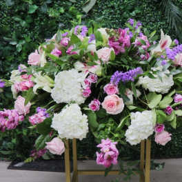 Large pink, white, and purple floral arrangement on a gold stand