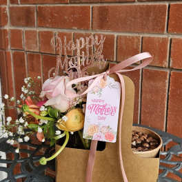 Pink and yellow flower arrangement in a kraft gift bag with a Mother's Day tag