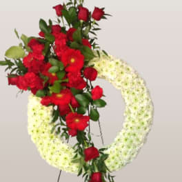 Standing floral wreath with red roses and white flowers on an easel