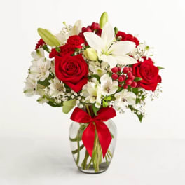 Red roses and white lilies in a glass vase with a red ribbon