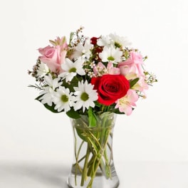 Mixed bouquet of roses and daisies in a clear glass vase