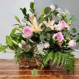 Pink roses and lilies arranged in a wicker basket