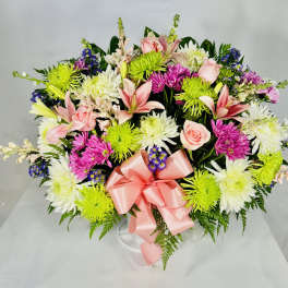 Mixed bouquet with pink lilies, roses, and white and green chrysanthemums tied with a pink ribbon