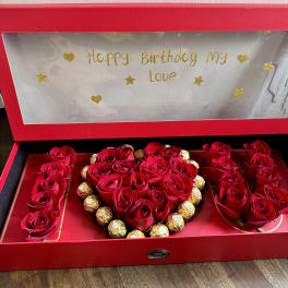 Red roses and chocolates arranged in a heart-shaped gift box