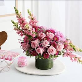 Pink roses and mixed pink flowers in a green vase on a table
