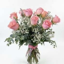 Pink roses arranged in a clear glass vase with baby's breath