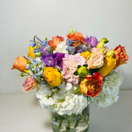 Colorful mixed bouquet in a clear glass vase with white hydrangeas