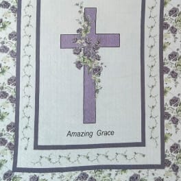 Quilt with a purple cross and floral border, labeled "Amazing Grace"
