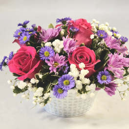 Pink roses and purple daisies in a white basket