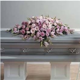 Pink and white mixed flower casket spray arranged on top of a gray casket