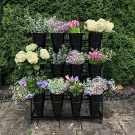 Outdoor stand with black cone vases filled with tulips, hydrangeas, and mixed pastel flowers.