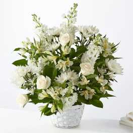 White roses and mixed white flowers in a white basket vase