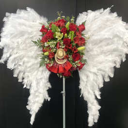Red rose arrangement with white feather wings on a stand