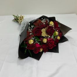 Bouquet of red roses with gold-wrapped chocolates in black paper