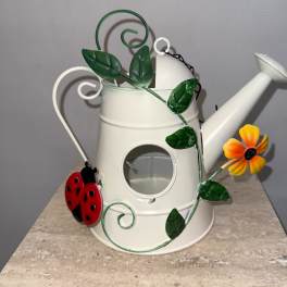 White metal watering can with decorative vine, flower, and ladybug accents