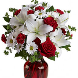 Red roses and white lilies in a red glass vase