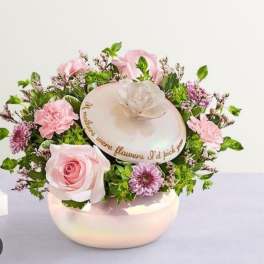 Pink roses and mixed blooms arranged in a round hatbox with a lid
