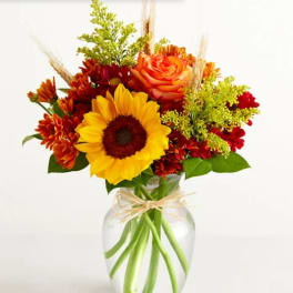Sunflower and orange rose bouquet in a clear glass vase