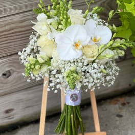White orchid and rose bouquet with baby's breath on a wooden easel