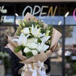 White lily and rose bouquet wrapped in kraft paper with ribbon