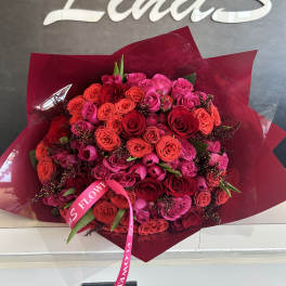 Large bouquet of red and pink roses wrapped in burgundy paper