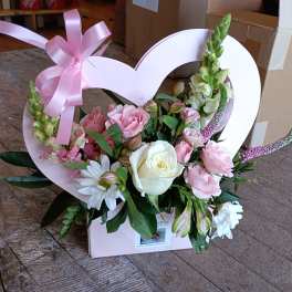 Pink and white floral arrangement in a heart-shaped box with a ribbon bow