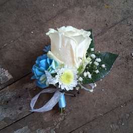 Small boutonniere with a white rose, blue flower, and white daisy