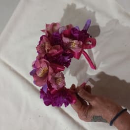 Pink and purple floral crown held in a hand