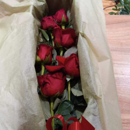 Bouquet of red roses wrapped in beige paper with a red ribbon