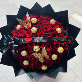 Heart-shaped bouquet of red roses with gold-wrapped chocolates and butterfly accents