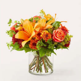 Orange lilies and roses in a clear glass vase