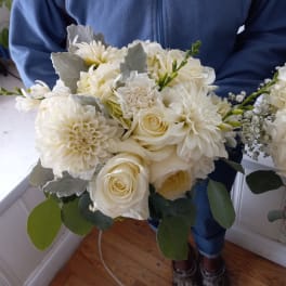 Person holding a white bouquet with roses and dahlias