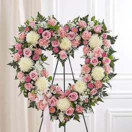 Heart-shaped standing wreath of pink and white flowers on a metal easel