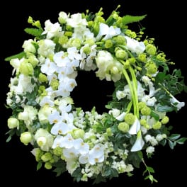 Large white and green floral wreath with orchids, roses, calla lilies, and pompom blooms