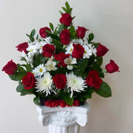 Red roses and white daisies arranged in a pedestal display